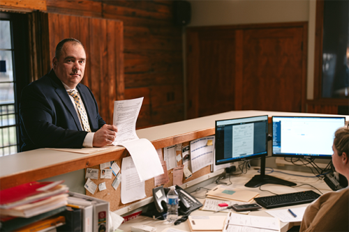 Tim Hayes chats at the lobby desk with his assistant over paperwork.