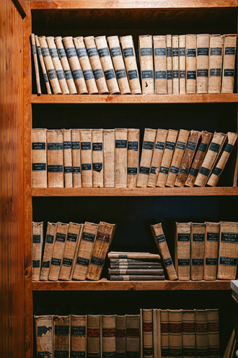 A 4 tier bookshelf filled with Law books. They appear to be well used and broken in.